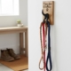 Oak dog lead holder with "Time for Walkies" engraving and a black dog-tail hook, mounted on a white wall in a clean entryway holding a leather, red, and blue leash.